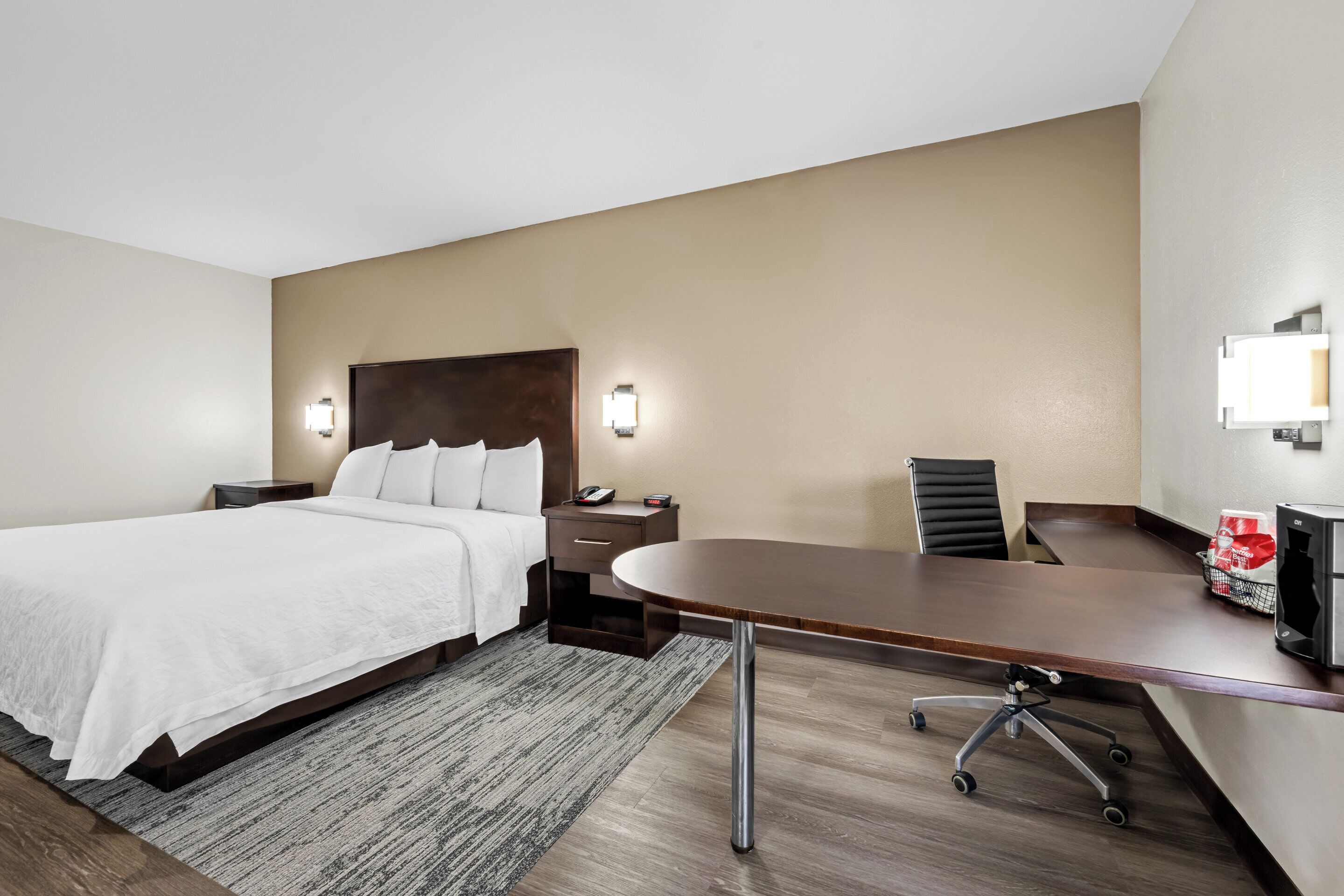 Una habitación de hotel con una cama, un escritorio, una silla y un televisor.