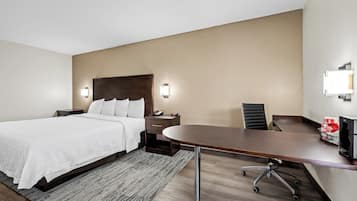 Una habitación de hotel con una cama, un escritorio, una silla y un televisor.