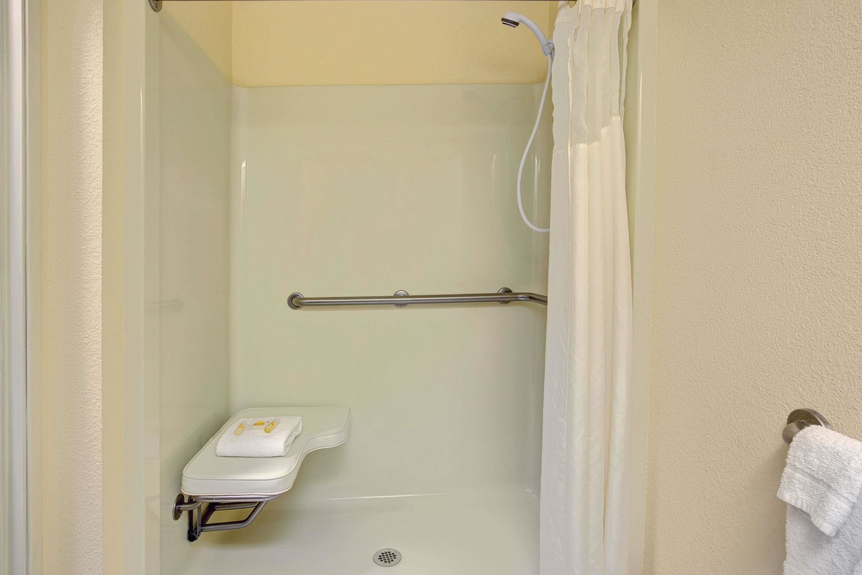 A small, enclosed shower area with a white toilet and a grab bar.