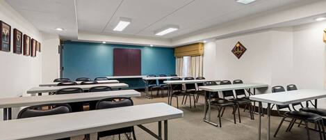 Un salón de conferencias con varias mesas y sillas, una pared azul grande y cuadros en la pared.