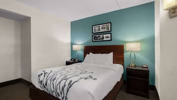 Habitación de hotel con una cama grande, dos mesitas de noche, una mesita auxiliar, un cabecero de madera y dos lámparas de pared.