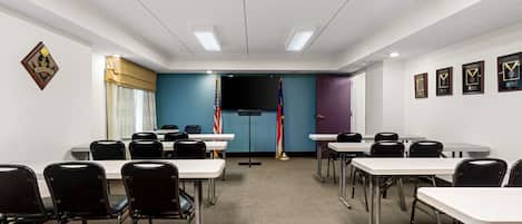 Un salón de conferencias con mesas, sillas, banderas y premios enmarcados en las paredes.