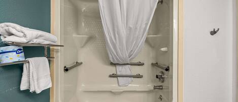 A bathroom with a bathtub, a shower curtain, a towel rack with towels, and a soap dish.