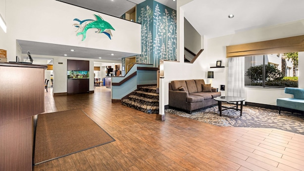 A spacious lobby with a wooden floor, a staircase, a reception desk, and a large green wall mural. - Sleep Inn Wilmington near University (Wilmington)
