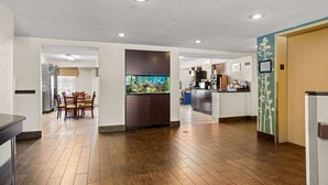 A modern kitchen with wooden cabinets, a dining area with chairs, and a large fish tank. - Sleep Inn Wilmington near University (Wilmington)