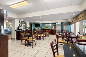 A modern restaurant with a kitchen area, dining tables, chairs, and a counter. - Sleep Inn Wilmington near University (Wilmington)