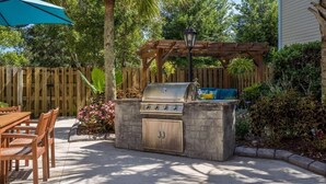 An outdoor kitchen with a grill, a wooden table, and chairs. - Sleep Inn Wilmington near University (Wilmington)