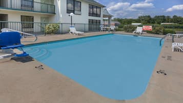 A swimming pool with lounge chairs and a lifeguard sign.
