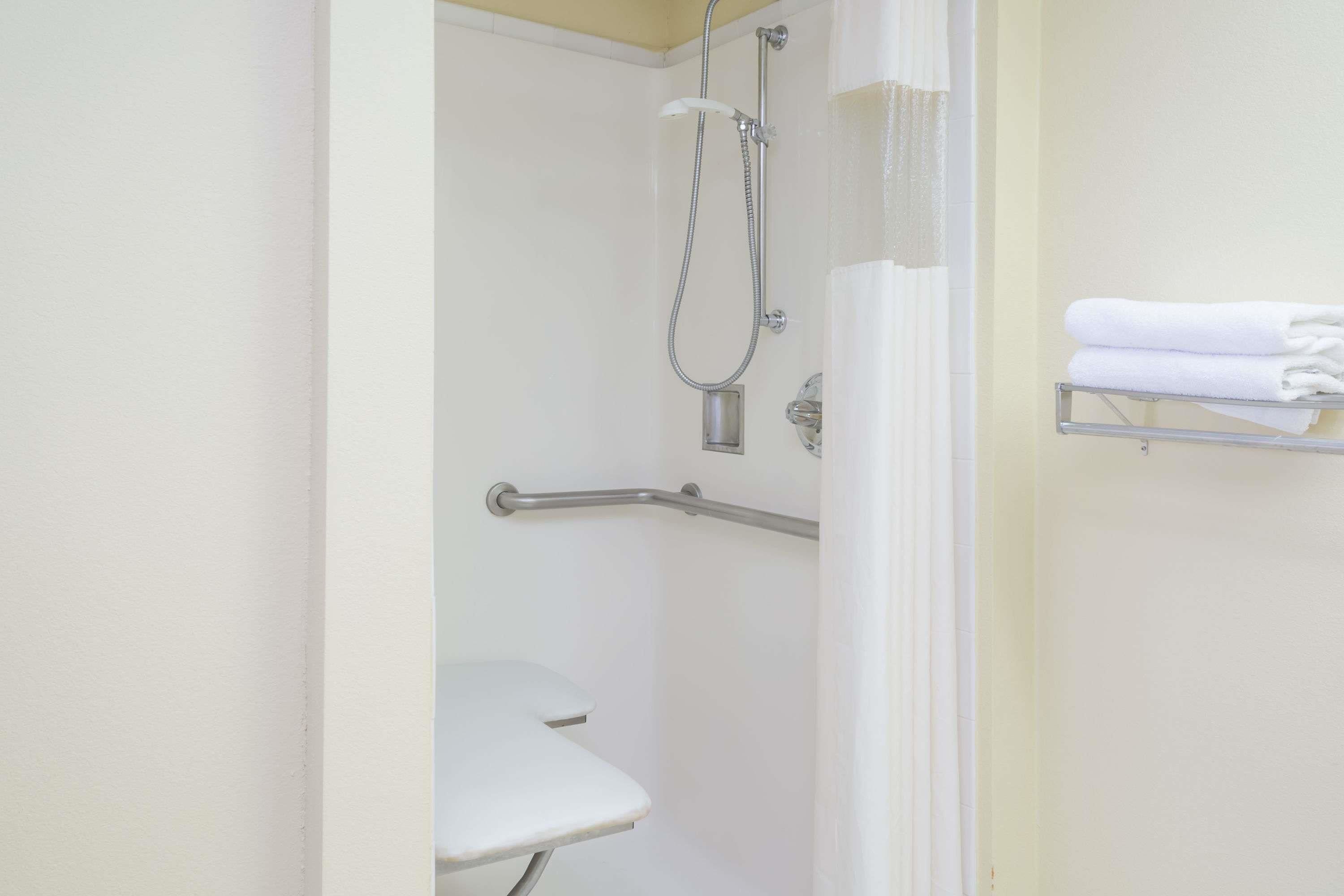 A bathroom with a shower, a white toilet, and a towel rack.