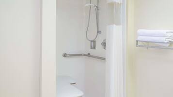 A bathroom with a shower, a white toilet, and a towel rack.