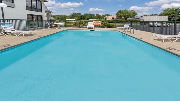 Ein rechteckiger Swimmingpool mit weißen Liegestühlen an beiden Seiten.