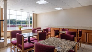 A dining area with tables and chairs, large windows, and a view of the outdoors. - Days Inn by Wyndham Lincolnton (Lincolnton)