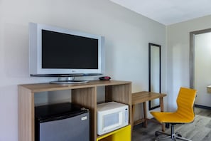 A modern room with a flat-screen TV on a wooden stand, a small refrigerator, a microwave, and a yellow chair. - Days Inn by Wyndham Lincolnton (Lincolnton)