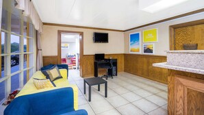 A hotel lobby with a blue sofa, a small table, a TV, and a reception desk. - Days Inn by Wyndham Lincolnton (Lincolnton)
