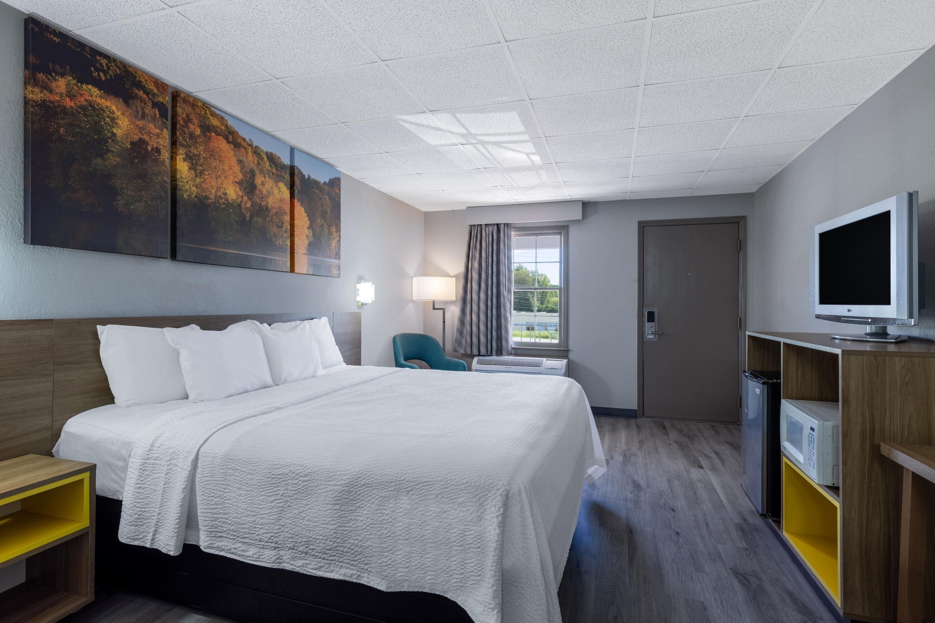 Une chambre d’hôtel avec un lit, une télévision, un bureau et une grande fenêtre.