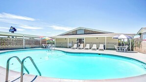 A swimming pool with lounge chairs and umbrellas, a Days Inn sign, and a pool building. - Days Inn by Wyndham Lincolnton (Lincolnton)