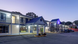 A motel with a covered parking area, multiple units, and a small garden. - Days Inn by Wyndham Lincolnton (Lincolnton)