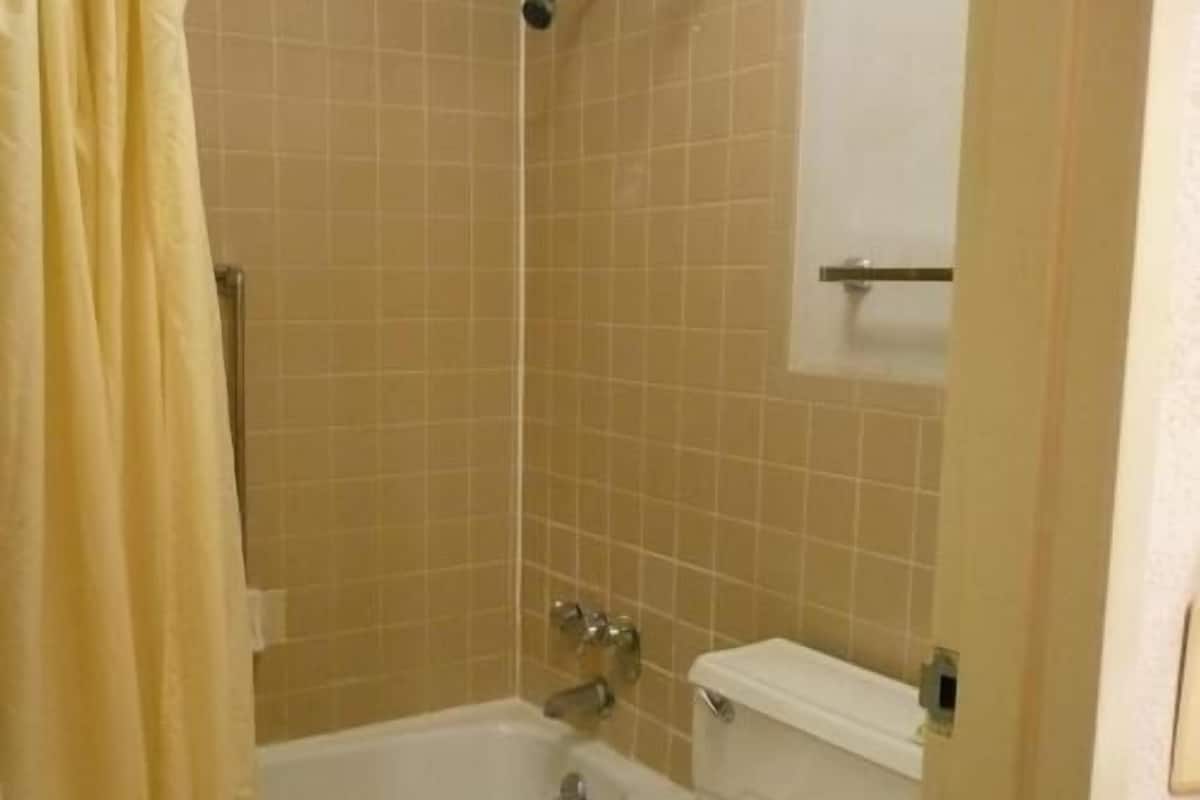 A bathroom with a bathtub, toilet, and a shower area.