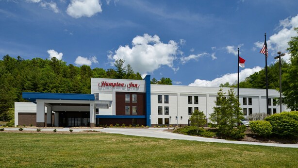 A Hampton Inn hotel with a modern design, featuring a prominent entrance and a parking lot.