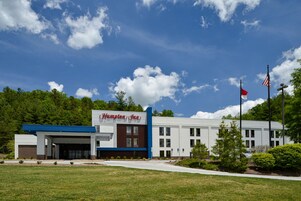 Un hotel Hampton Inn con diseño moderno, que destaca por su entrada principal y un estacionamiento.