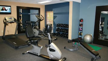 A gym with treadmills, an elliptical, a bench press, dumbbells, and a stationary bike.