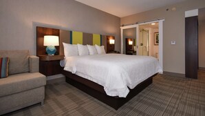 A hotel room with a large bed, a bedside table with a lamp, a chair, and a mirror. - Hampton Inn Brevard (Pisgah Forest)