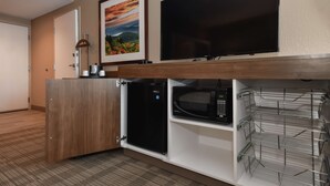 A hotel room with a wooden desk, a flat-screen TV, a microwave, and a refrigerator. - Hampton Inn Brevard (Pisgah Forest)