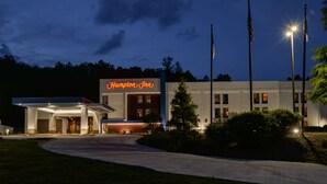 A Hampton Inn hotel with a well-lit entrance and a clear view of the building's name. - Hampton Inn Brevard (Pisgah Forest)