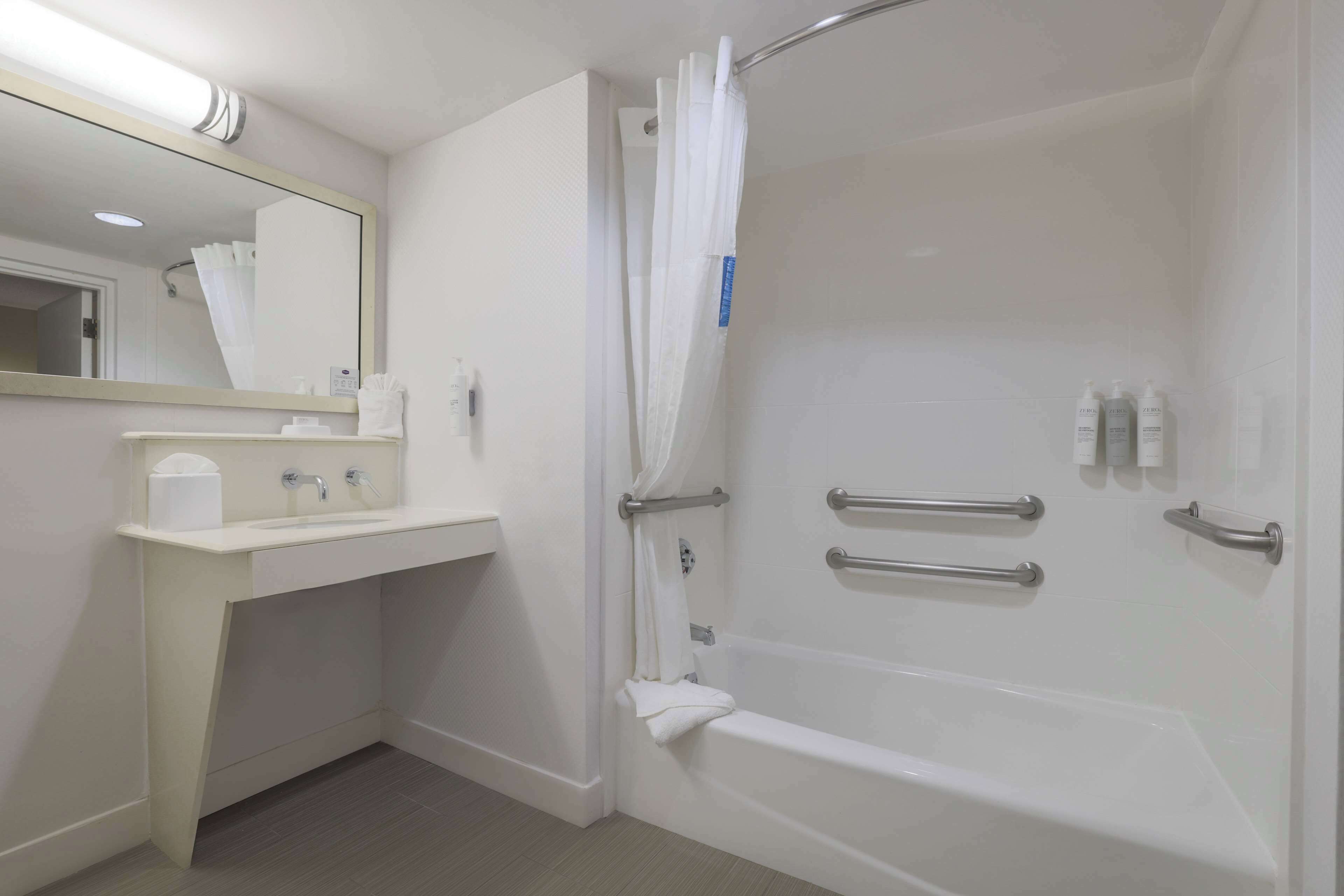 Un baño moderno con bañera, lavabo, espejo y cortina de ducha.