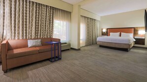 Una habitación de hotel con sofá, una mesita, cama y televisión.