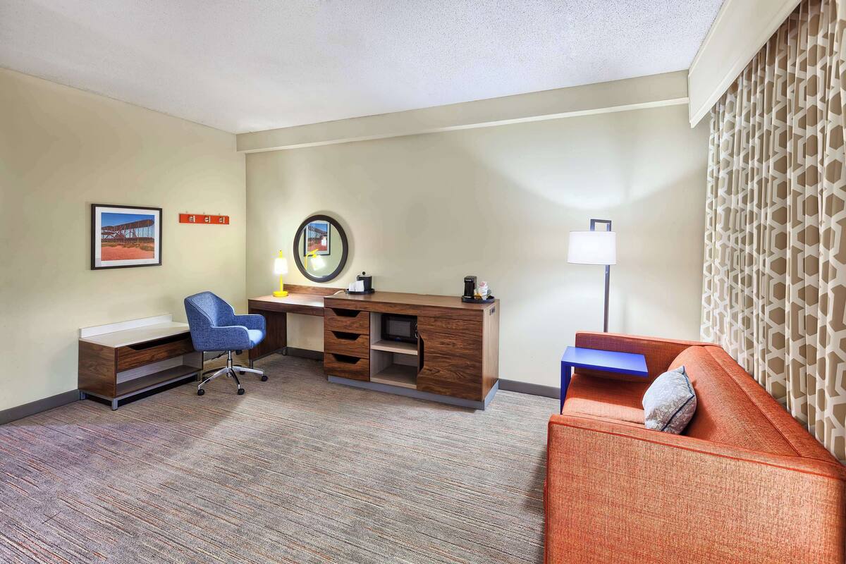 Una habitación de hotel con escritorio, silla y sofá.