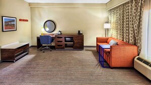 Una habitación de hotel con escritorio, silla y sofá naranja.