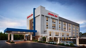 A Hampton Inn hotel with a modern design, featuring a large entrance canopy and a swimming pool area. - Hampton Inn by Hilton Concord/Kannapolis (Concord)