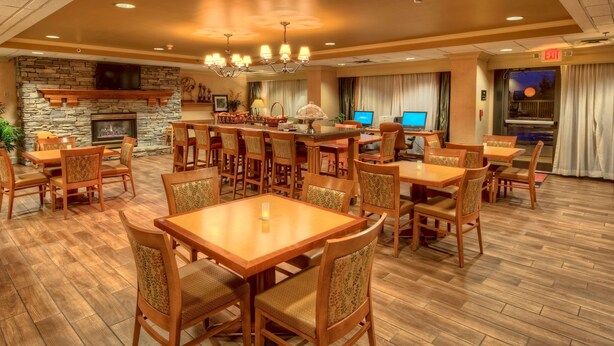 A spacious dining area with wooden tables and chairs, a stone fireplace, and a television mounted on the wall. - Hampton Inn by Hilton Concord/Kannapolis (Concord)