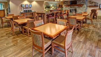 Un comedor amplio con mesas y sillas de madera, una chimenea de piedra y una barra de café con varios dispensadores.