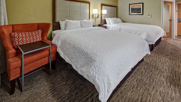 A hotel room with two beds, a sofa, a small table, and a carpeted floor.