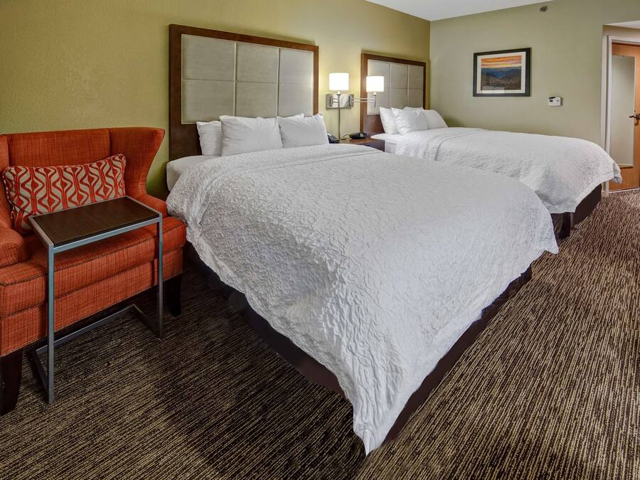 A hotel room with two beds, a sofa, a small table, and a carpeted floor.