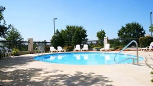 A rectangular swimming pool with a metal ladder, surrounded by white lounge chairs and a brick border. - Hampton Inn by Hilton Concord/Kannapolis (Concord)