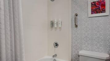 A bathroom with a shower, a toilet, and a bathtub. There are toiletries on the wall.