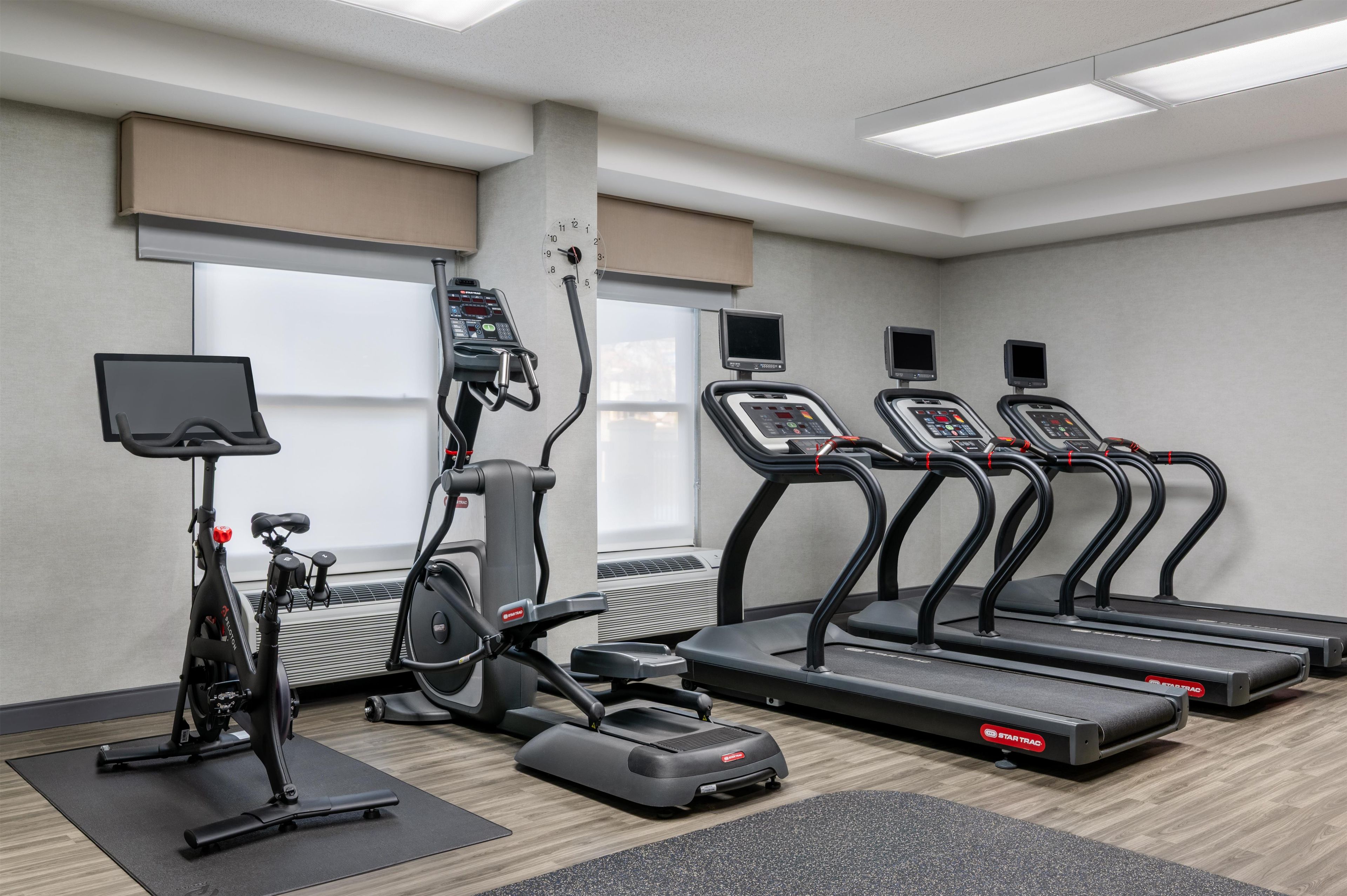 Un gimnasio con cintas de correr, elípticas y una bicicleta estática.