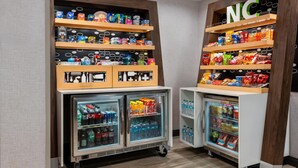 Ein Selbstbedienungsbereich mit Speisen und Getränken, inklusive Kühlregalen und Regalen voller Snacks und Erfrischungen.