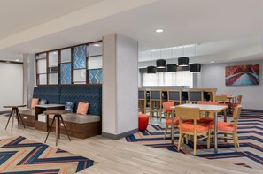 A modern hotel lobby with a seating area, tables, and chairs. - Hampton Inn Eden (Eden)