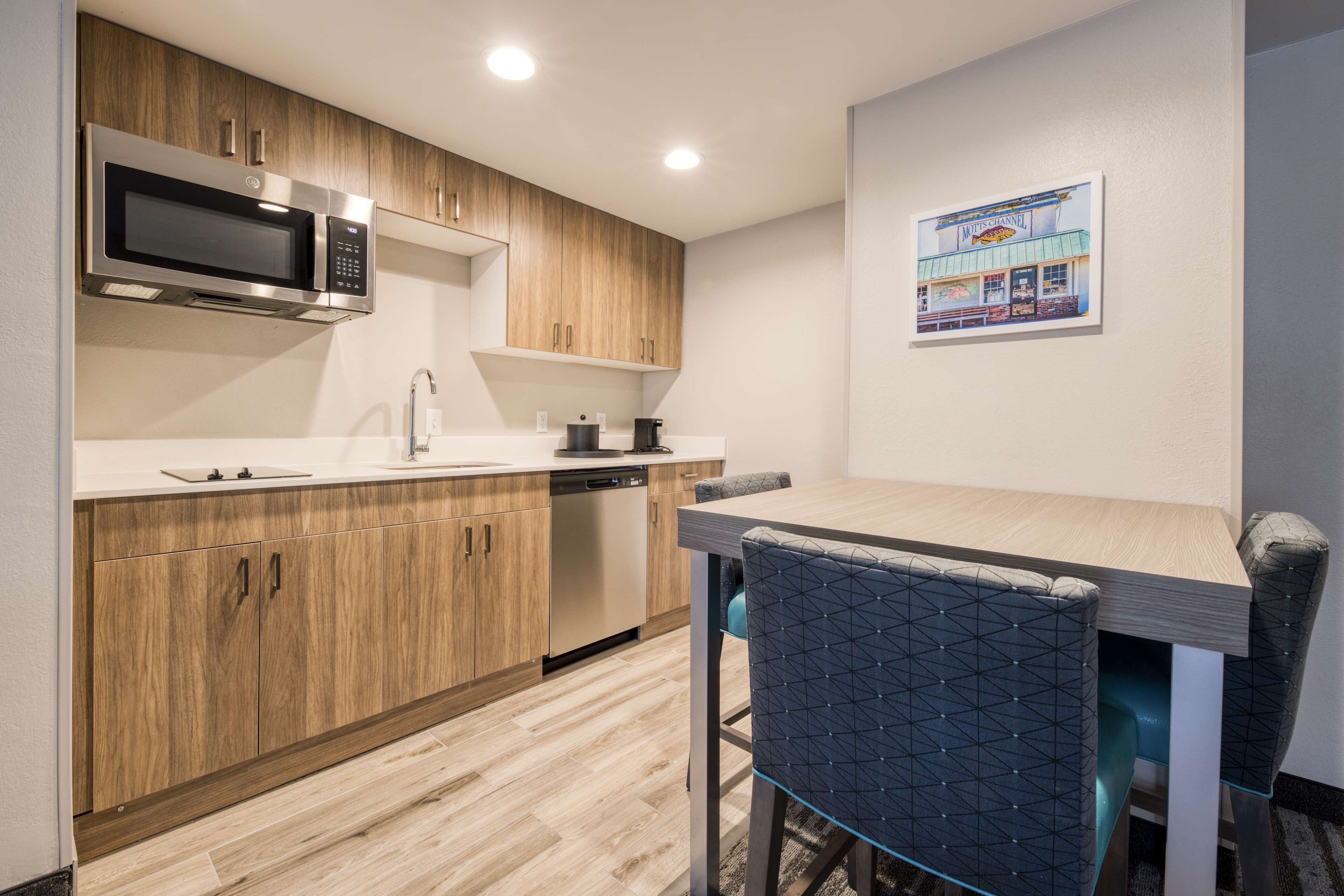 A modern kitchen with wooden cabinets, a built-in microwave, and a dining area with a table and chairs.