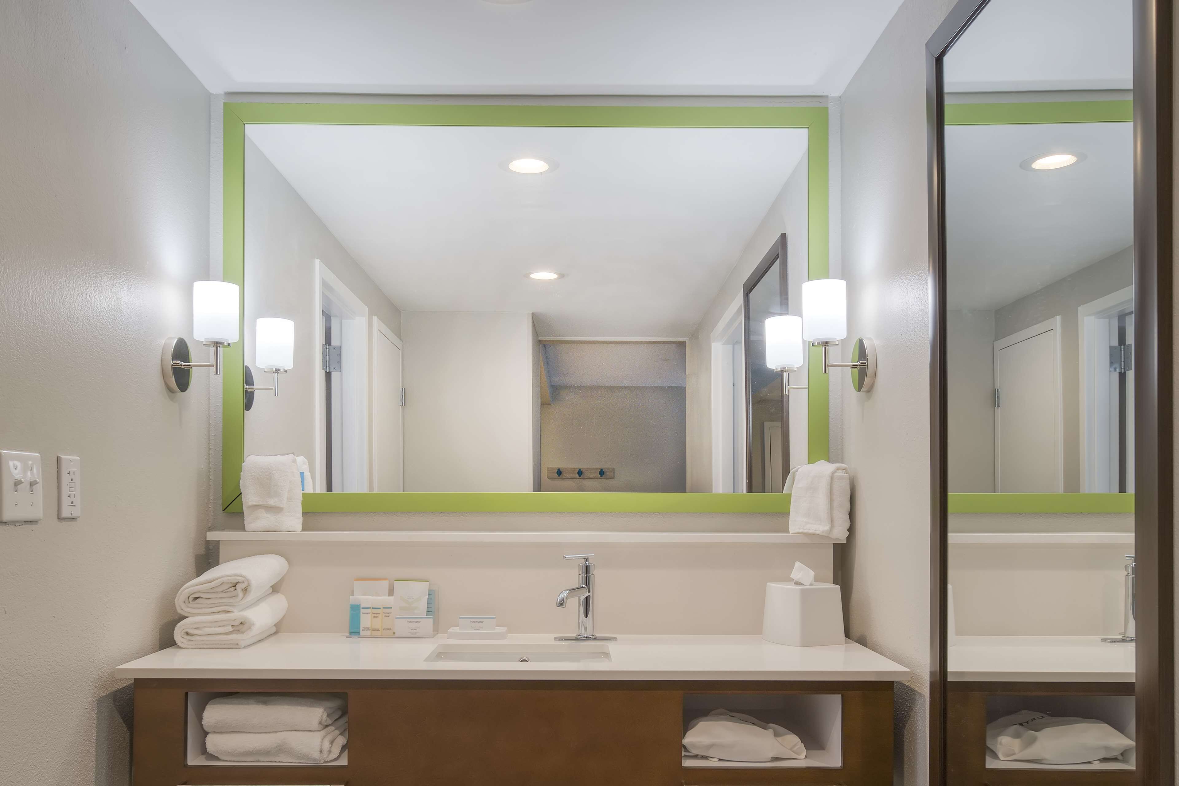 A bathroom with a large mirror, white sink, and two towel racks.