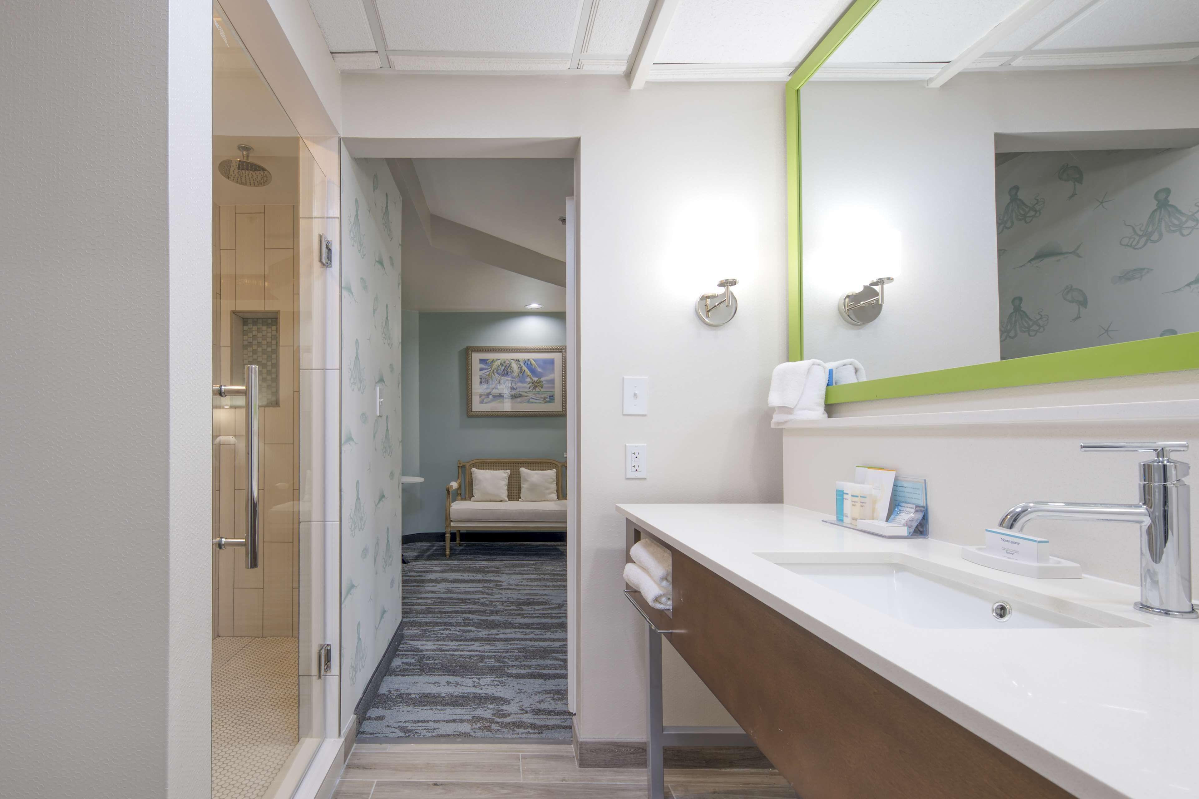 Un baño moderno con un espejo grande, un lavabo y una zona de ducha.