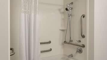 Une salle de bain moderne équipée d’une baignoire, d’une douche et de barres d’appui.