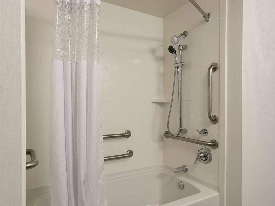 Ein modernes Badezimmer mit Badewanne, Dusche und Haltegriffen.