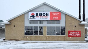 A BISON Inn & Suites building with a sign indicating microwave and fridge, weekly specials, and under new management. - Bison Inn & Suites on University (Fargo)