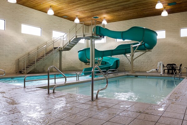 An indoor swimming pool with two slides, a staircase, and a seating area. - Comfort Inn Bismarck (Bismarck)