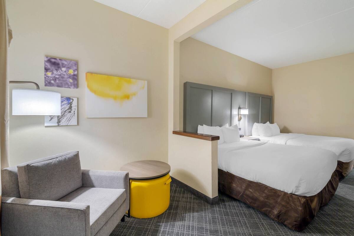 A hotel room with a bed, a sofa, a small round table, and artwork on the walls.